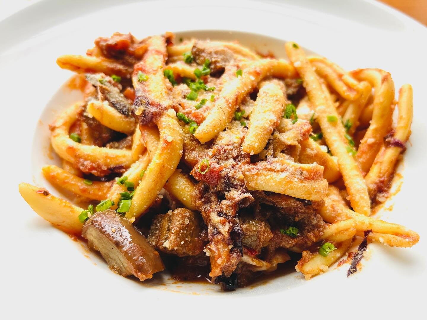 Short, twisted pasta with meat ragu, grated cheese, and green herbs.