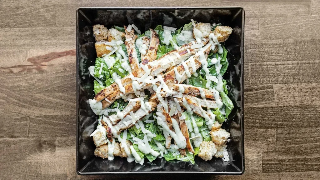 Overhead shot of a Caesar salad with grilled chicken and croutons.