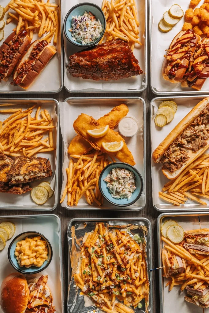 Flat lay of diverse American comfort foods on nine metal trays.