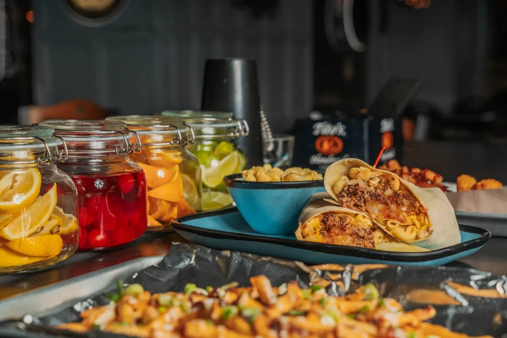 A cut burrito, mac and cheese, fries, and beverage garnishes.