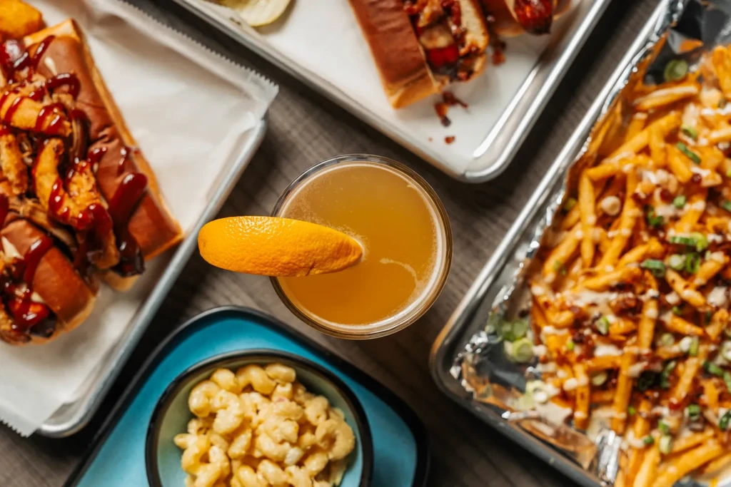 Overhead shot of hot dogs, mac and cheese, cocktail, and loaded fries.