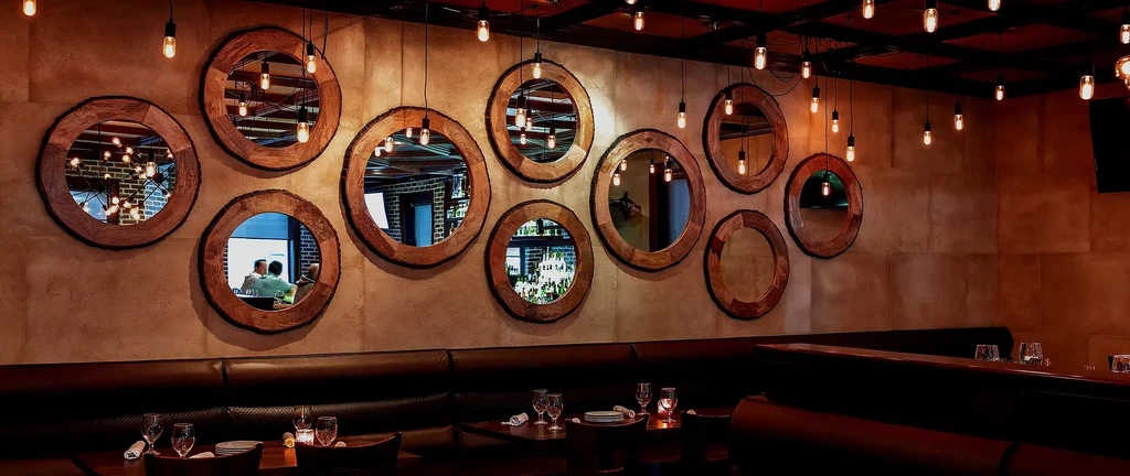 Restaurant interior with wood-framed mirrors, leather booths, and warm light.
