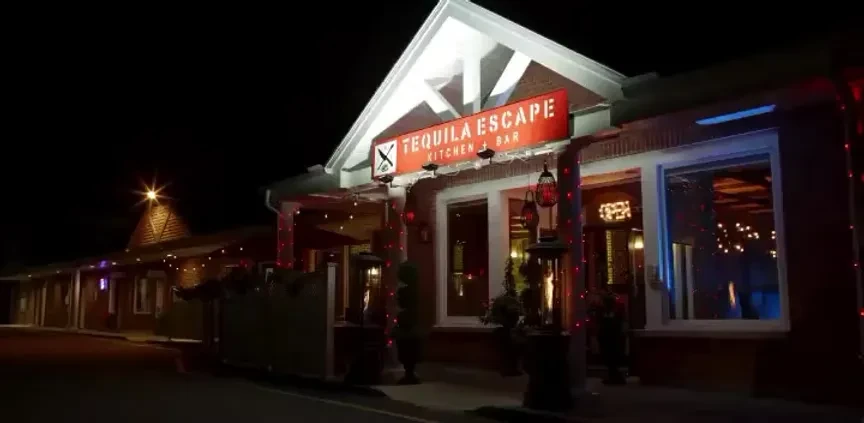 Exterior of Tequila Escape Kitchen + Bar, lit at night with string lights.