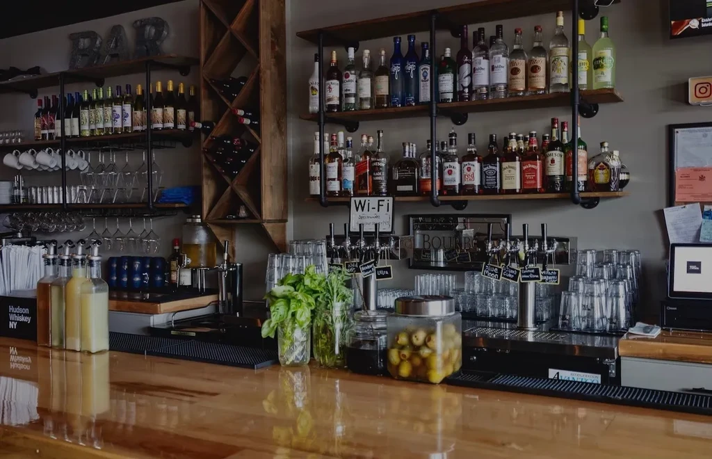 A well-stocked bar with liquor, wine, and a wooden counter.