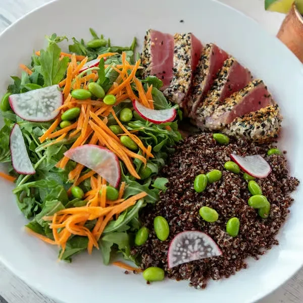 Seared tuna with quinoa, arugula, edamame, shredded carrots, and radishes.