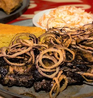 Grilled ribs topped with onions, served with cornbread and coleslaw.