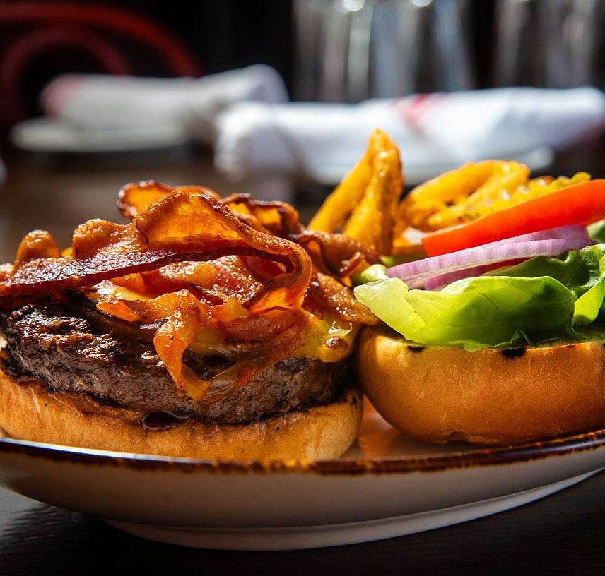 Bacon cheeseburger with caramelized onions, lettuce, tomato, and fries.
