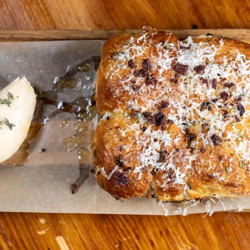 Savory bread with cheese and bacon crumbles on a wooden board.