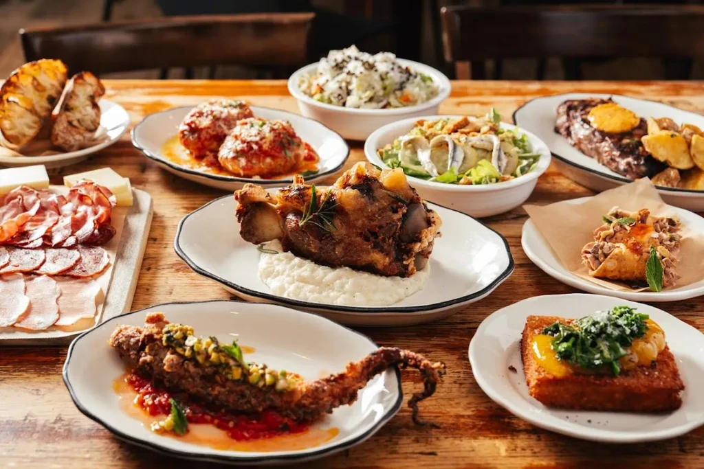 A wooden table laden with various plates of food, including meats and salads.