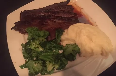 A white plate with brisket, mashed potatoes, and broccoli.