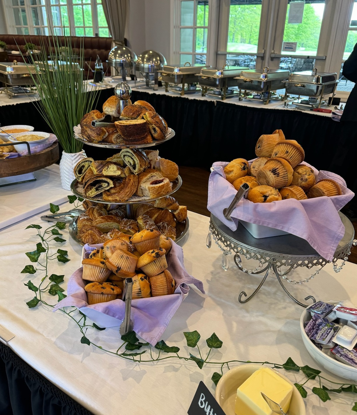 Buffet table with various pastries, muffins, butter, and chafing dishes.