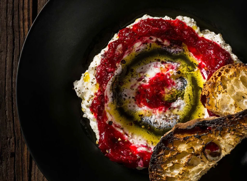 White dip with red and green swirls, served with toasted bread.