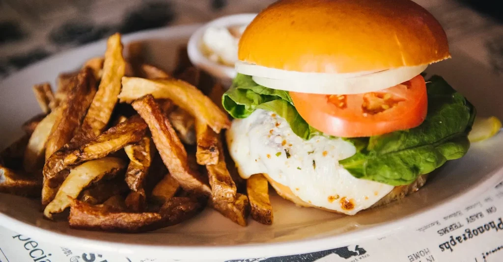 A plate of fries and a burger with lettuce, tomato, onion.