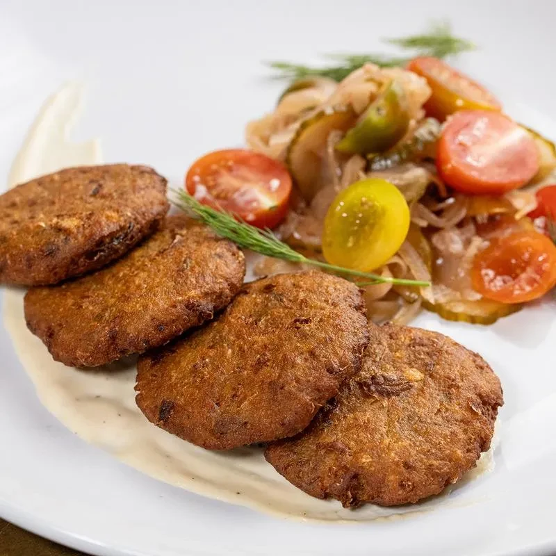 Five fried patties with mixed vegetable salad on a white plate.