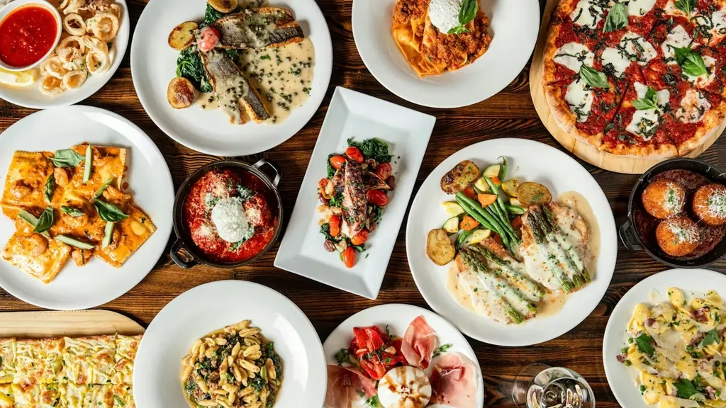 Overhead shot of a rustic table laden with diverse Italian dishes.