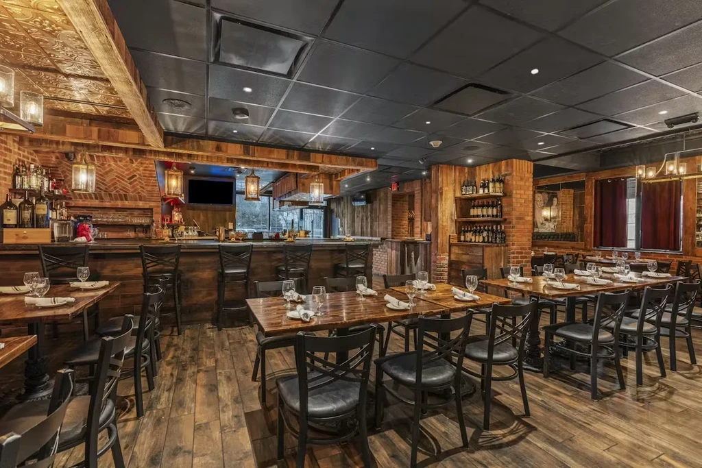Empty, warm, rustic restaurant interior with dining area and bar.