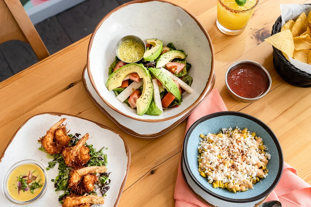 Overhead view of a meal with salad, shrimp, corn, salsa, and margarita.