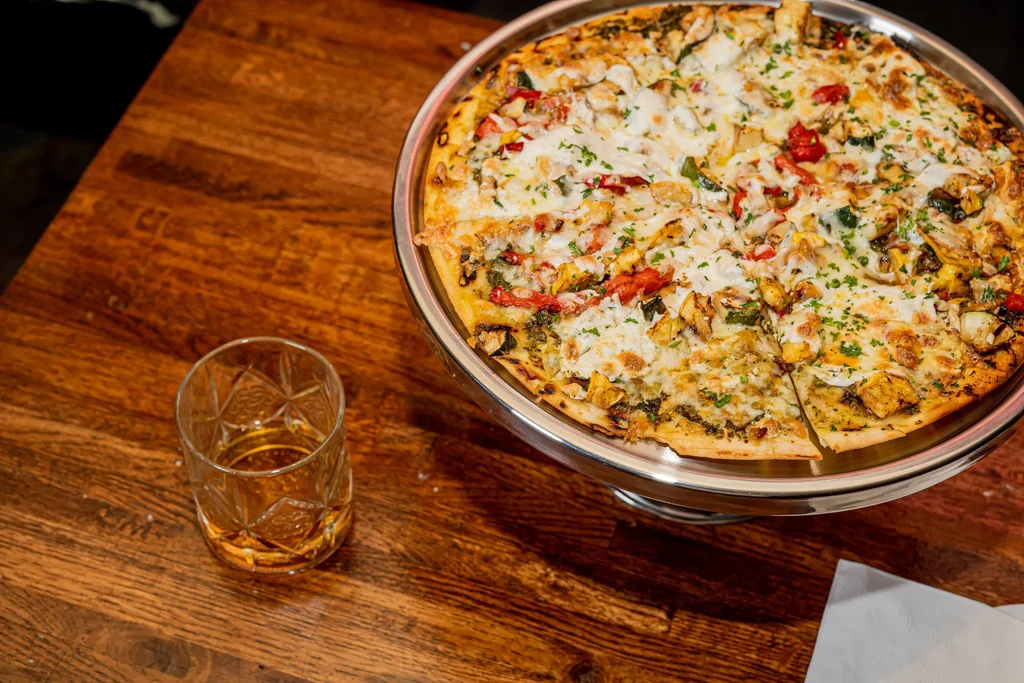 A half-eaten pizza and a drink on a wooden table.