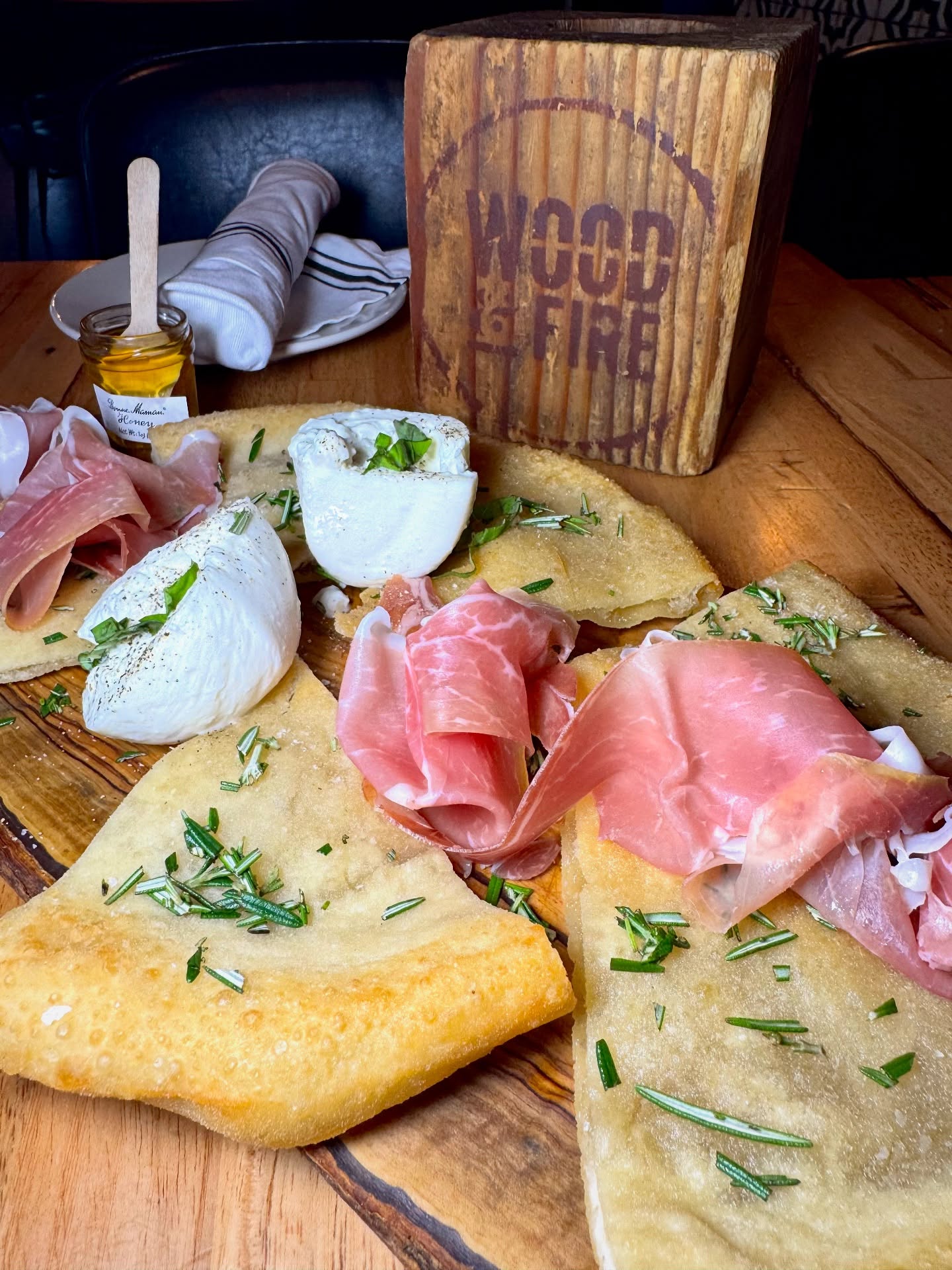 Fried flatbread with burrata, prosciutto, rosemary, and a honey pot.