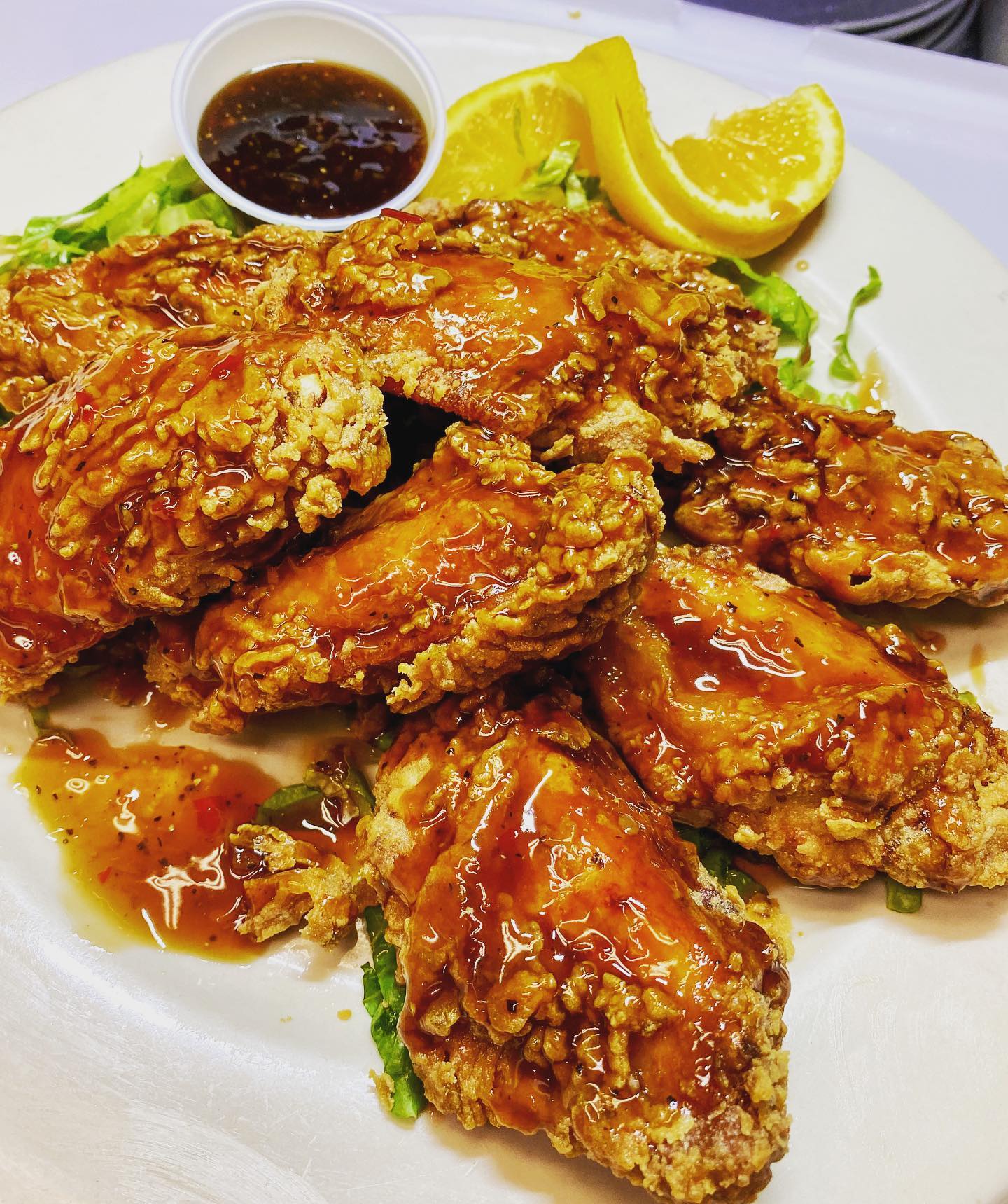 Glazed fried chicken pieces, orange slices, and dipping sauce.