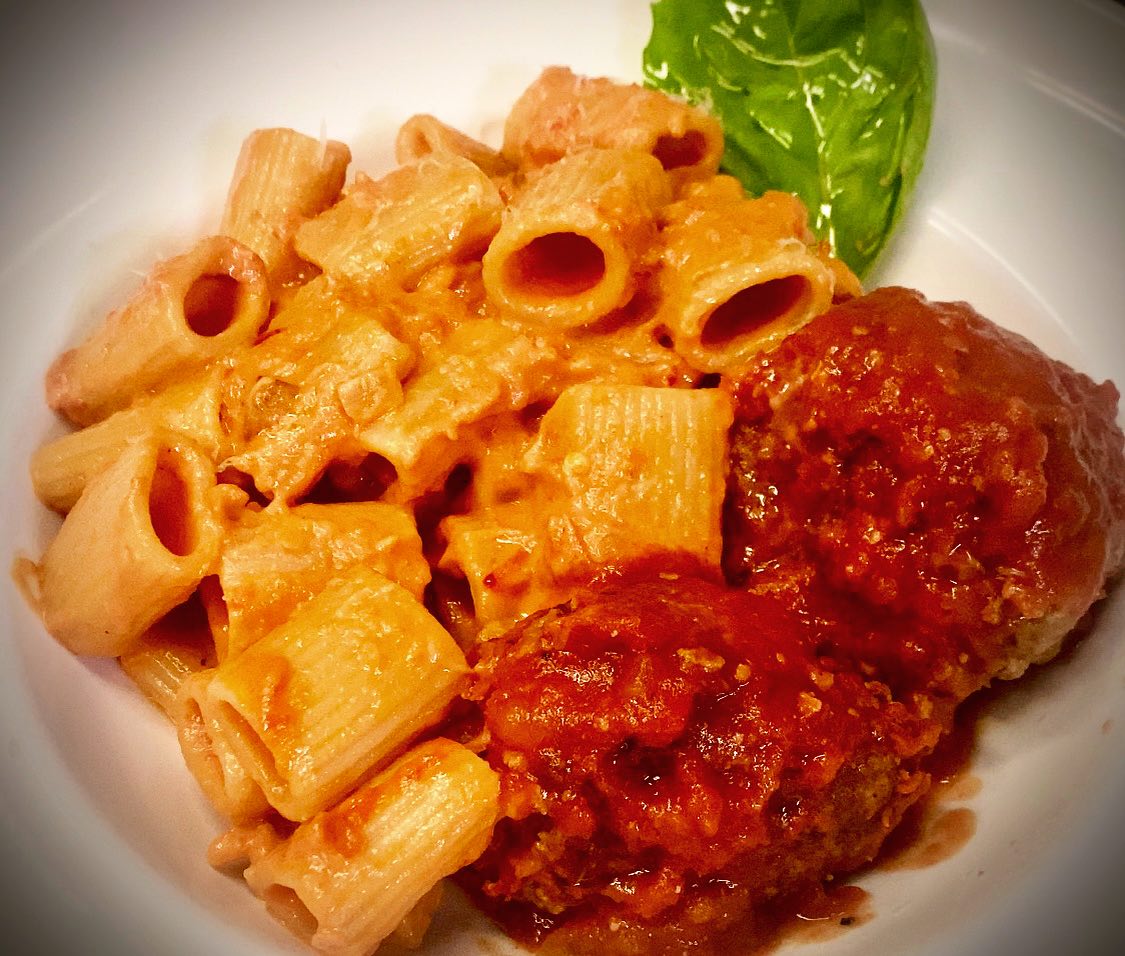 Pasta with creamy sauce, meat in tomato sauce, and a basil leaf.