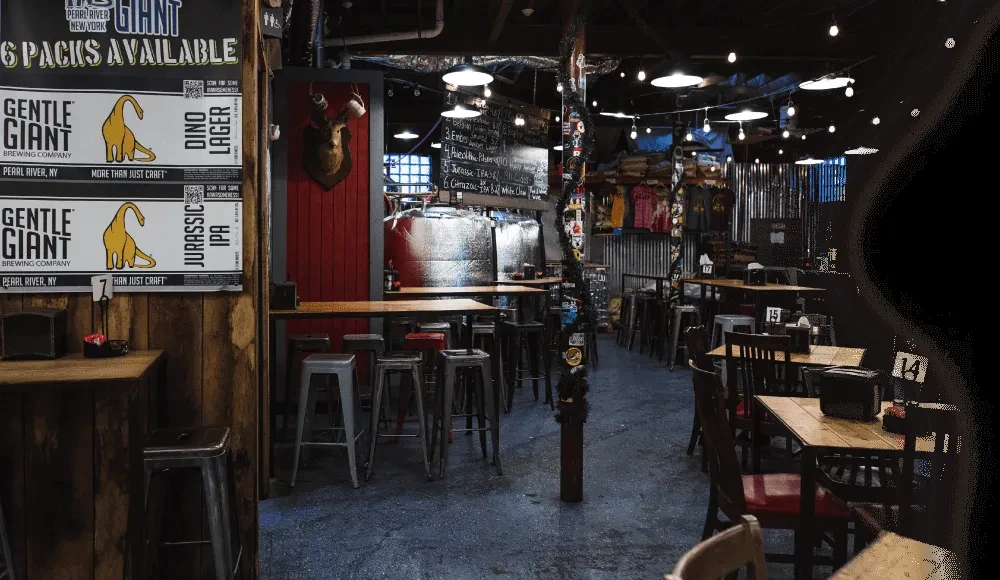 Interior of a brewery with tables, bar stools, and brewing equipment.