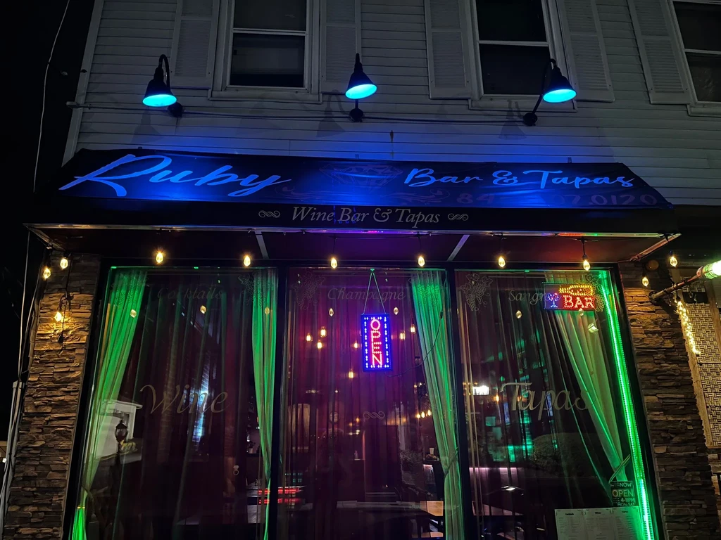 Exterior of Ruby Bar & Tapas with blue and green lighting at night.