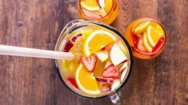 Pitcher of sangria with sliced fruit, two glasses of sangria.