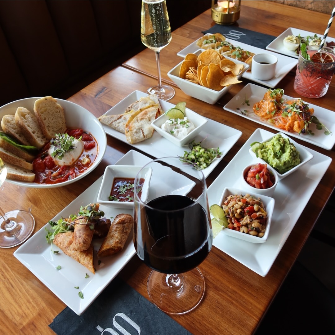 Table covered with various small plates of food and drinks.