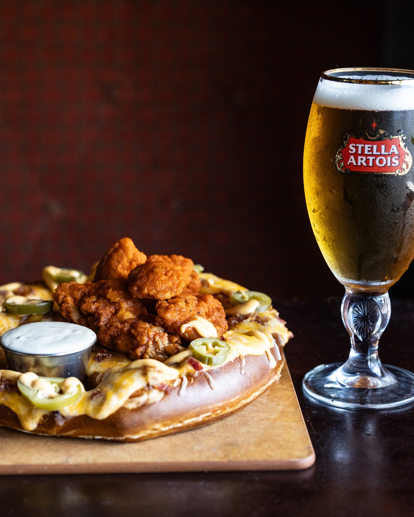 Pretzel topped with fried chicken, cheese, jalapeños, and a Stella Artois.