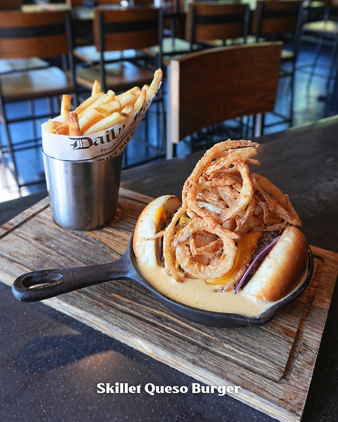Skillet queso burger with onion rings and fries.