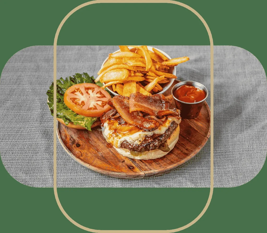 A bacon cheeseburger with a side of fries and ketchup on a wooden plate.