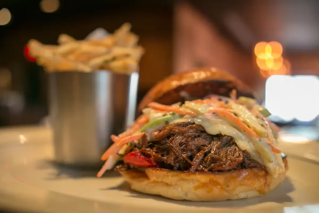 Pulled pork sandwich with coleslaw and a side of fries.
