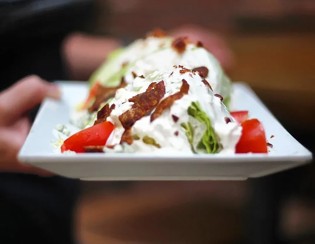 Two wedge salads with bacon, tomatoes, and blue cheese dressing.