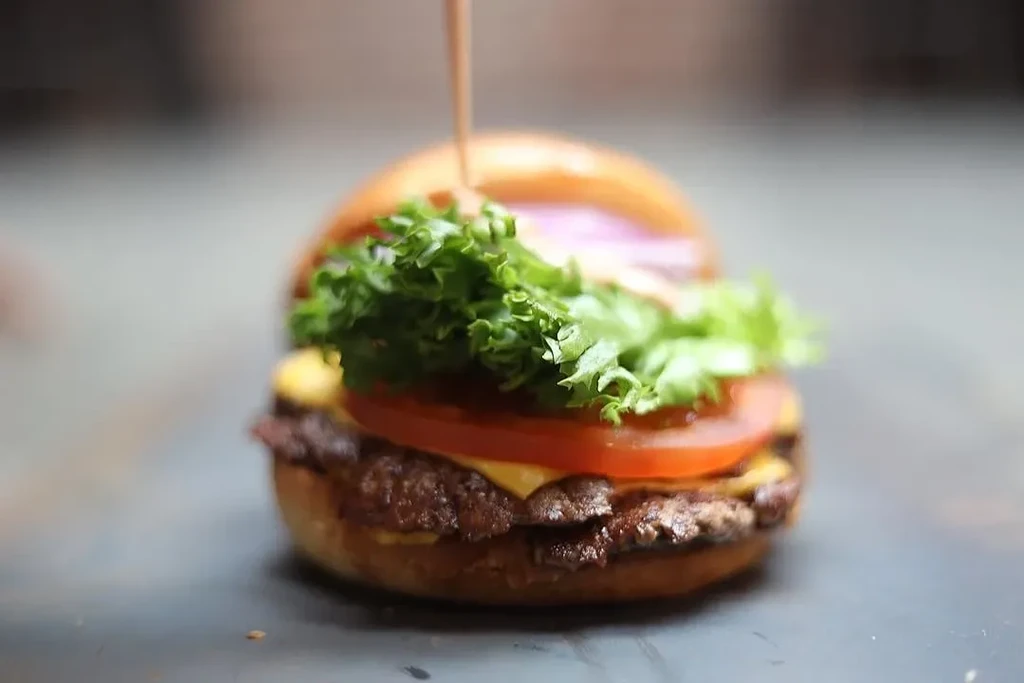 A double smash burger with lettuce, tomato, cheese, and red onion.