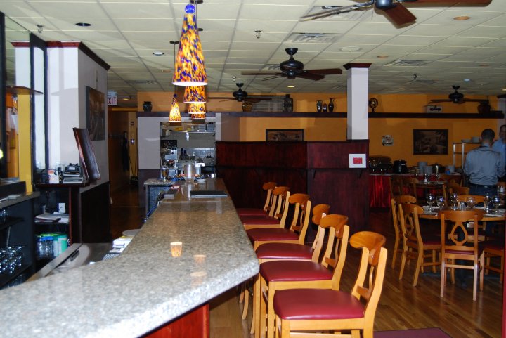 Interior of a restaurant with a bar, dining tables, and ceiling fans.