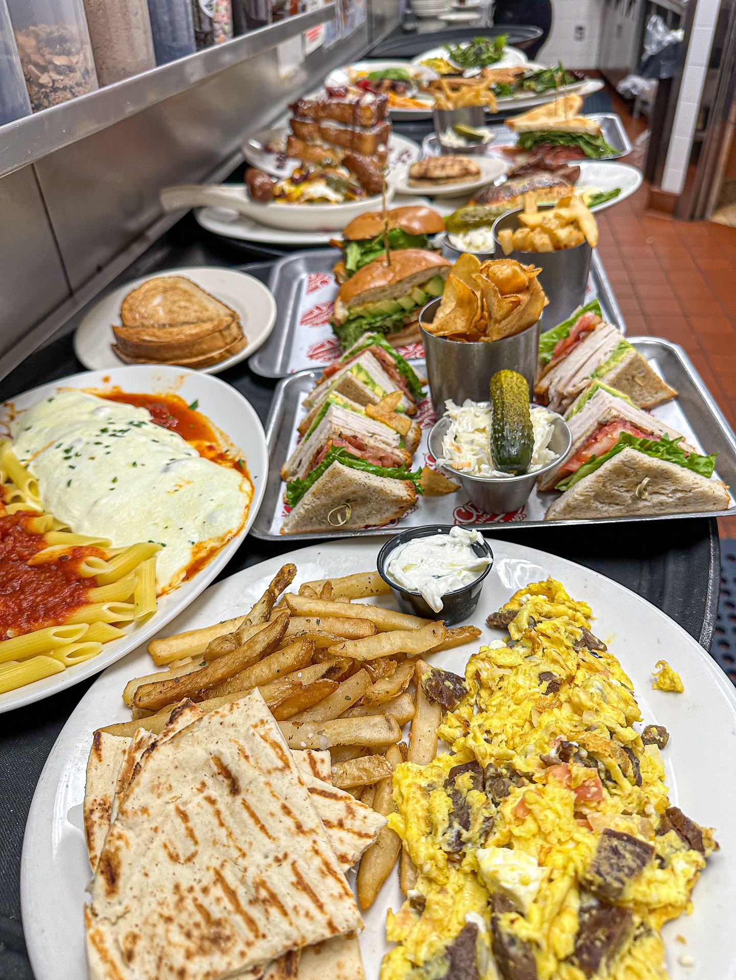 Assortment of diner food including sandwiches, fries, eggs, and pasta.
