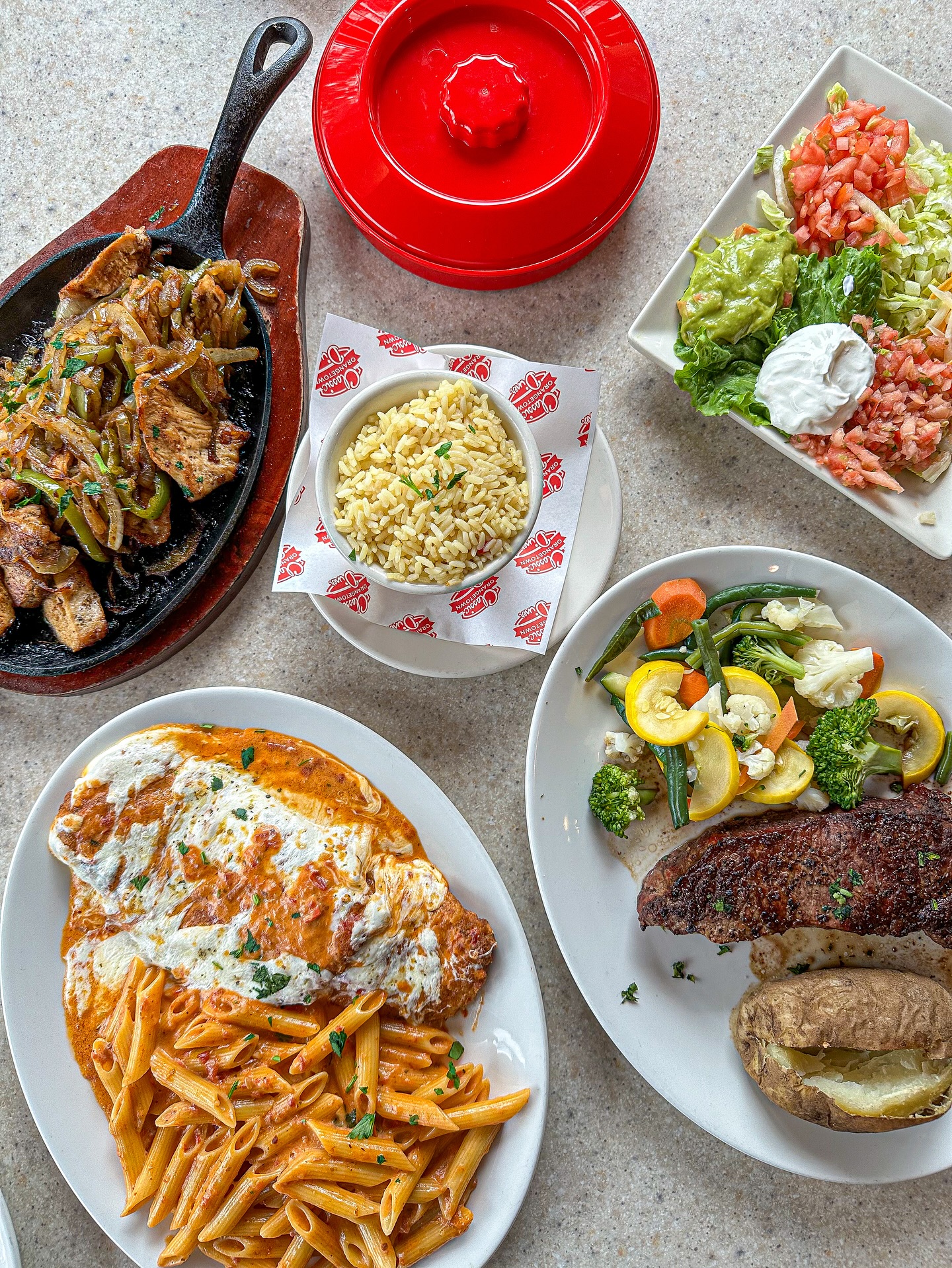Assortment of chicken fajitas, pasta, steak, and various side dishes.