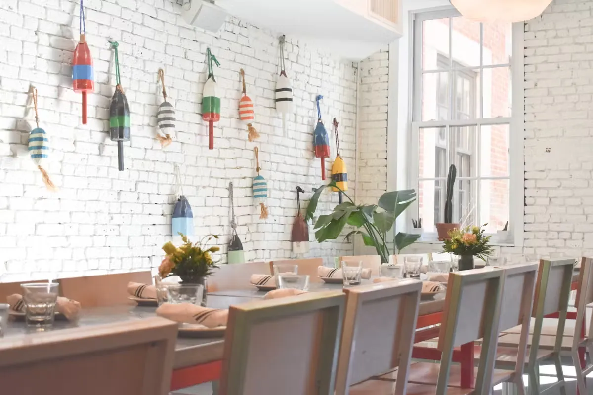 Restaurant dining room with white brick walls decorated with colorful buoys.
