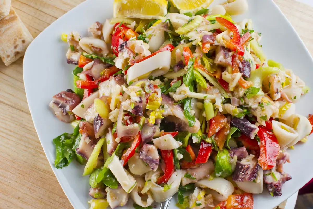 A plate of squid and octopus salad with red bell peppers.