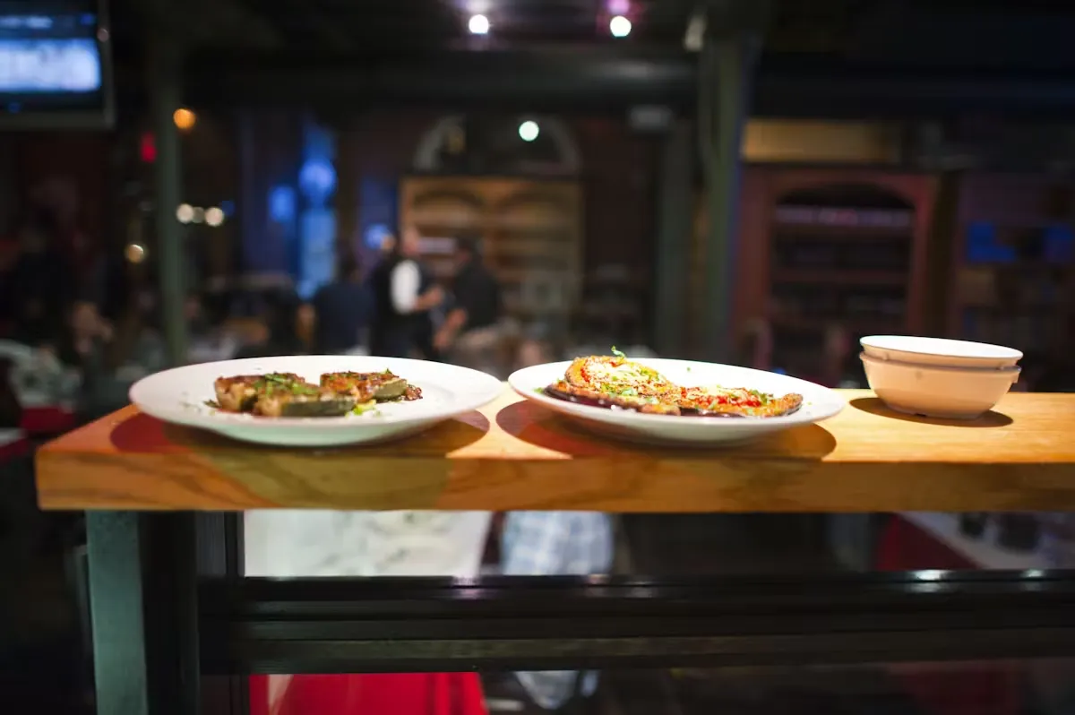 Two plates of food and bowls on a counter in a blurred restaurant.