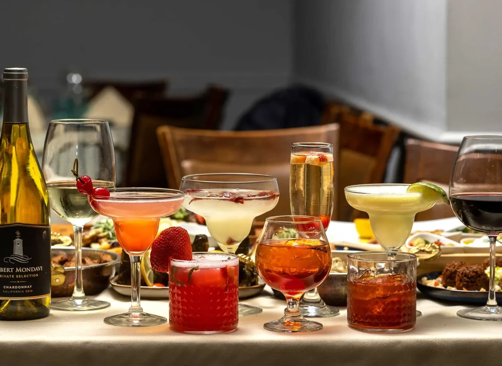 A variety of cocktails, wine, and drinks on a dinner table.