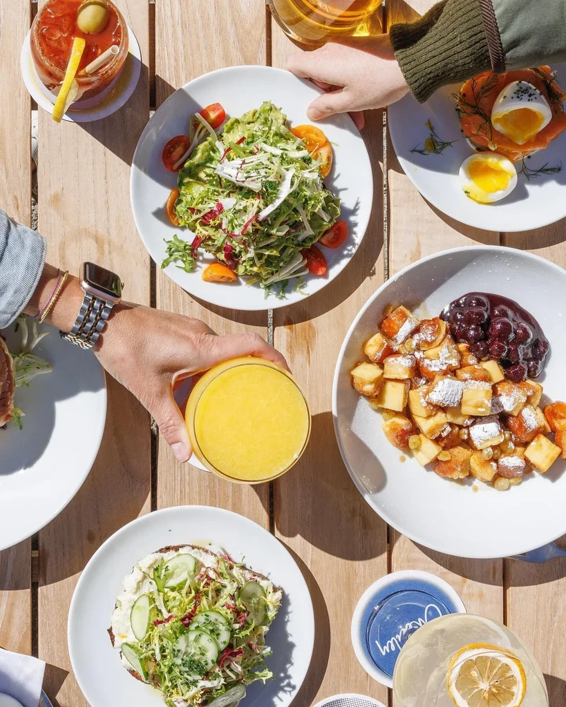 Overhead view of several plates of brunch food on a wooden table.