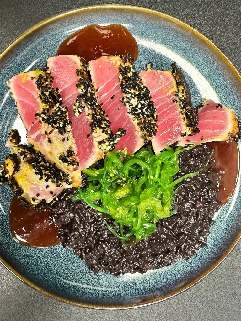 Sesame-crusted seared tuna with black rice, seaweed salad, and sauce.