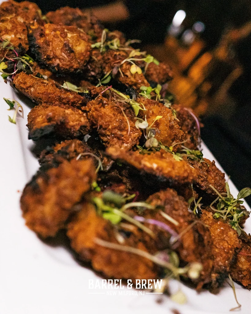 Close-up of crispy fried chicken wings garnished with microgreens.
