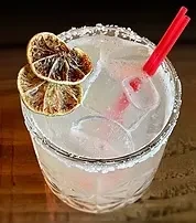 A glass of margarita with dried lime slices and red straws.