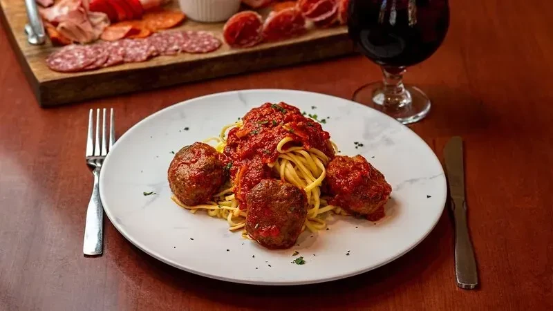 Spaghetti with meatballs and marinara sauce on a white plate.