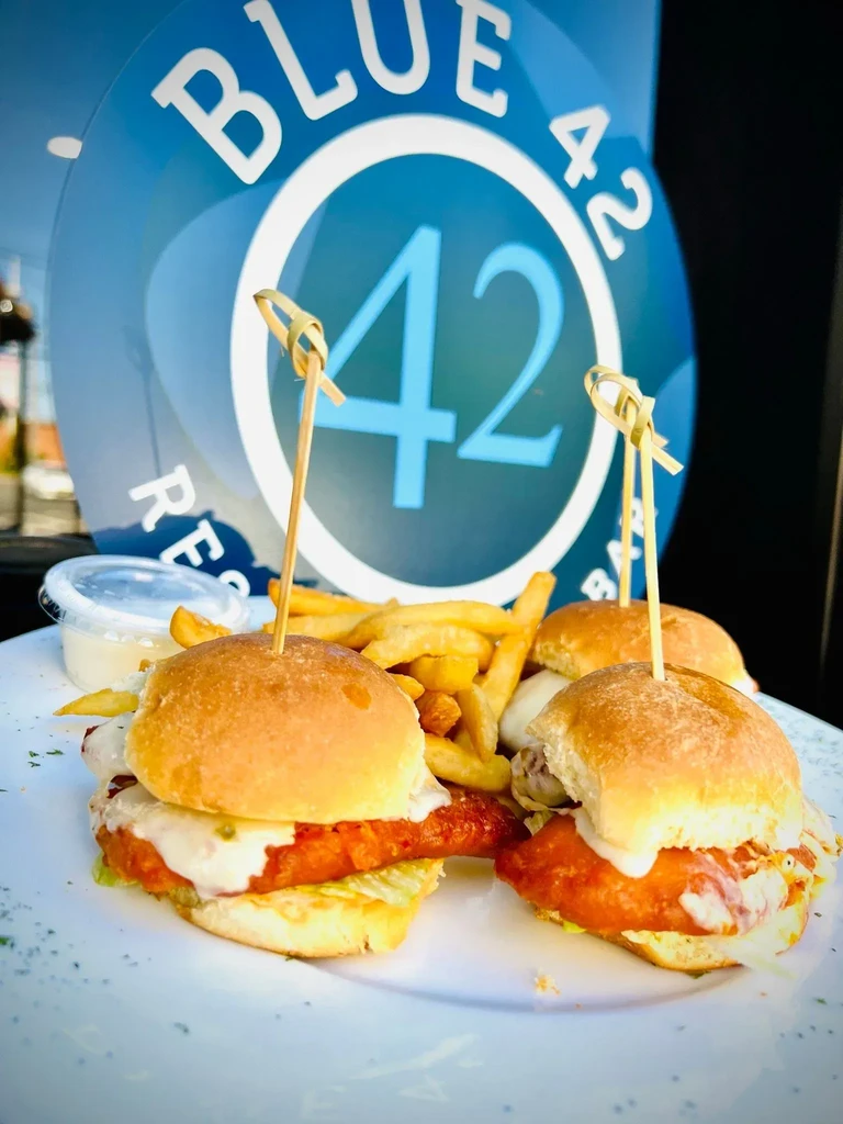 Sliders, fries, and sauce on a plate with "BLUE 42" sign.