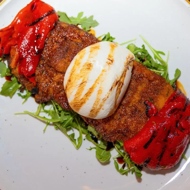 Fried cutlet with grilled mozzarella, red peppers, and arugula.