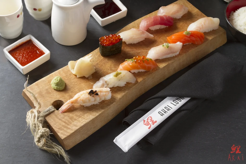 Various colorful sushi pieces, wasabi, and pickled ginger on a wooden board.